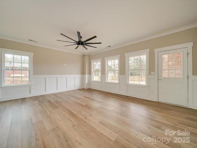 spare room with ceiling fan, ornamental molding, and light wood-type flooring