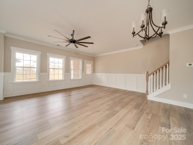 unfurnished living room with ceiling fan with notable chandelier, crown molding, and light hardwood / wood-style floors