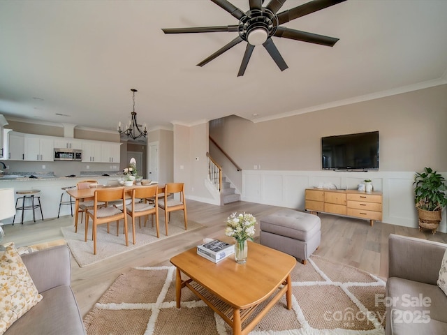 living room with ceiling fan with notable chandelier, sink, light hardwood / wood-style flooring, and ornamental molding