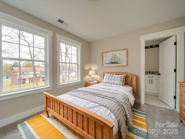 bedroom with light carpet and connected bathroom