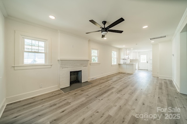 unfurnished living room with ceiling fan, crown molding, a fireplace, and light hardwood / wood-style flooring