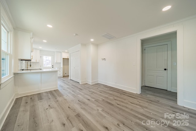 unfurnished living room with light hardwood / wood-style floors and crown molding