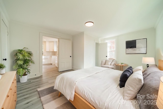 bedroom featuring connected bathroom, ornamental molding, and light wood-type flooring