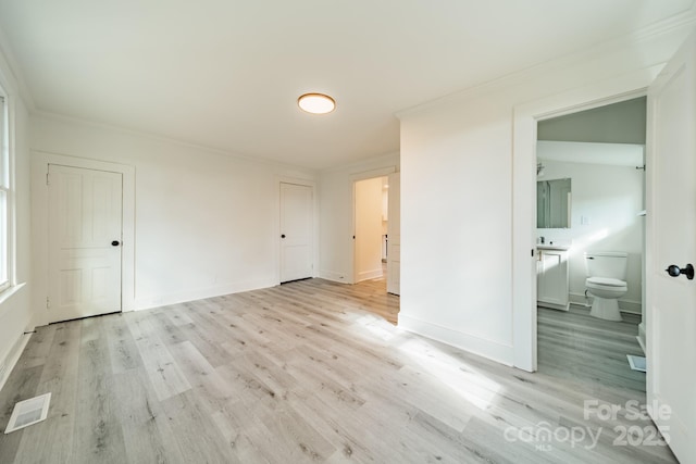 spare room with crown molding and light wood-type flooring