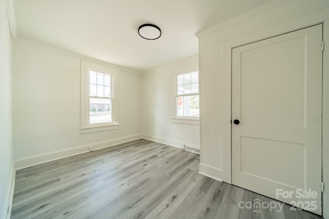 empty room featuring crown molding and light hardwood / wood-style floors