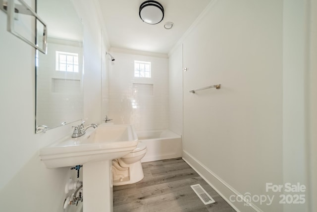 bathroom with wood-type flooring, tiled shower / bath combo, toilet, and crown molding