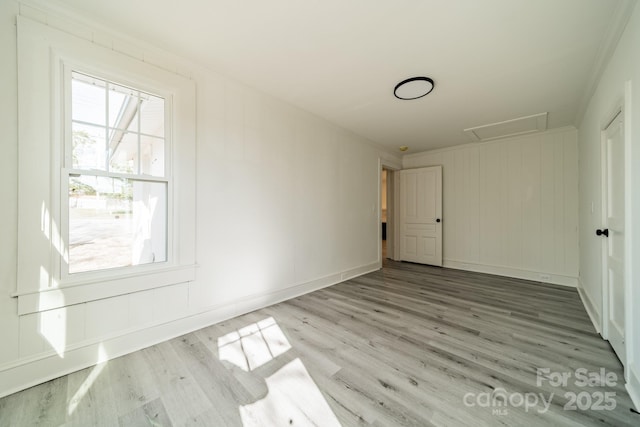 empty room featuring light wood-type flooring and ornamental molding