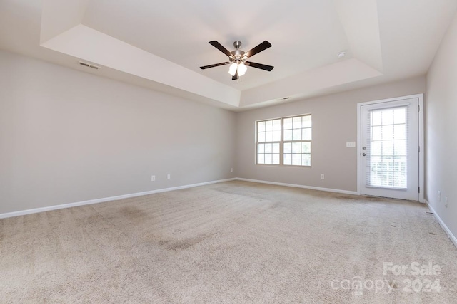 unfurnished room featuring ceiling fan, light carpet, and a tray ceiling