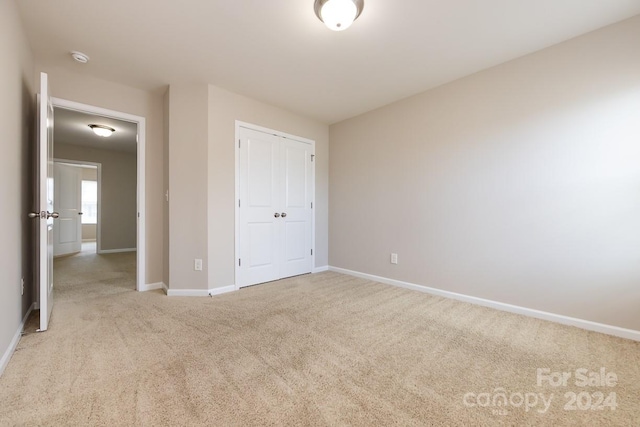 unfurnished bedroom featuring a closet and light colored carpet