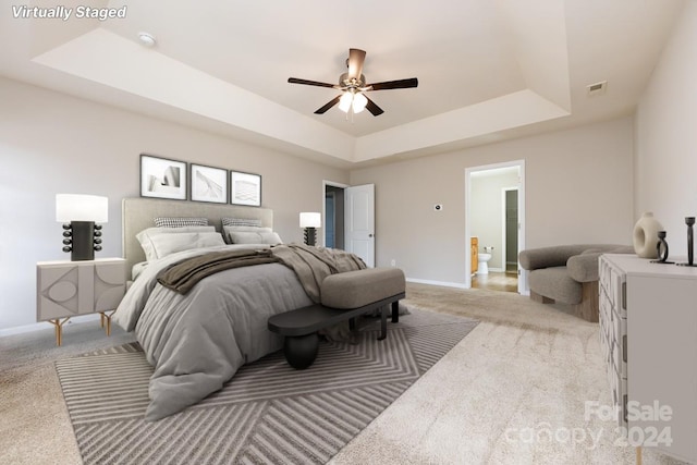 carpeted bedroom with a tray ceiling and ceiling fan