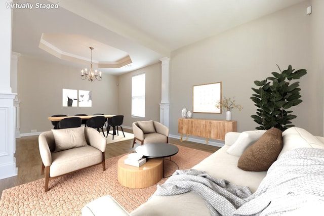 living room featuring decorative columns, a raised ceiling, hardwood / wood-style flooring, and a notable chandelier