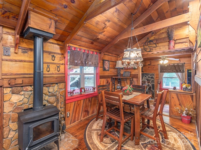 dining area with vaulted ceiling with beams, wood ceiling, wooden walls, hardwood / wood-style flooring, and ceiling fan