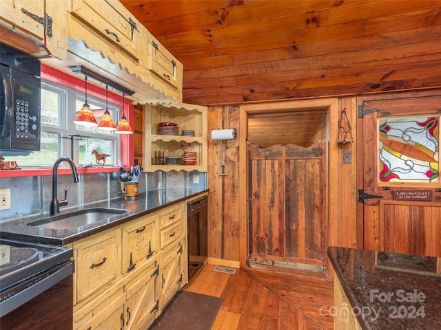 kitchen featuring sink, black appliances, hanging light fixtures, dark wood-type flooring, and wooden walls