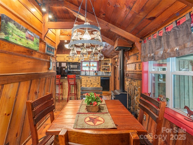 dining area with wooden ceiling, an inviting chandelier, lofted ceiling with beams, and wooden walls