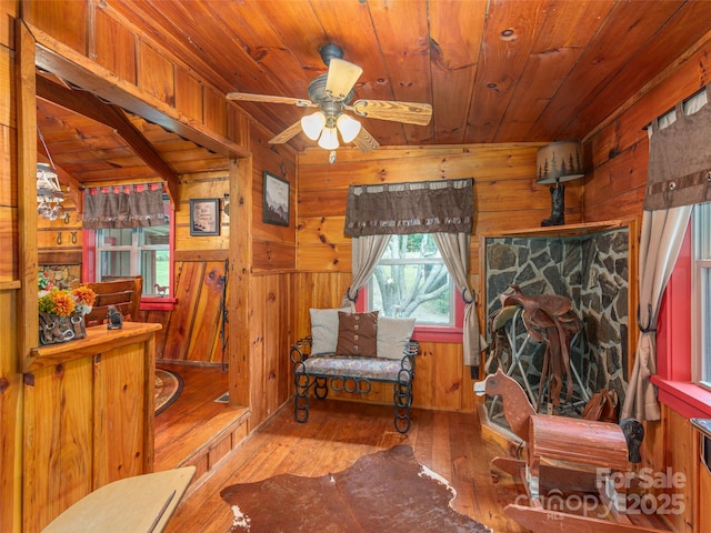 living area featuring hardwood / wood-style floors, wood walls, wood ceiling, and ceiling fan
