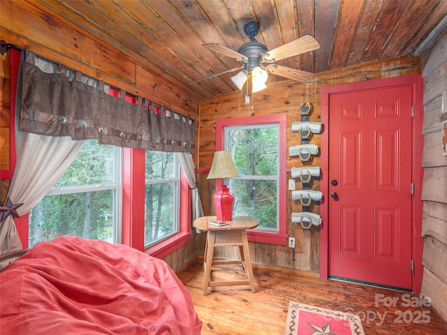 foyer with wood ceiling, ceiling fan, wood finished floors, and wooden walls