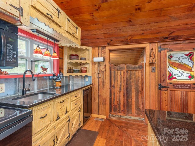 kitchen with wood finished floors, a sink, black appliances, wooden walls, and wood ceiling