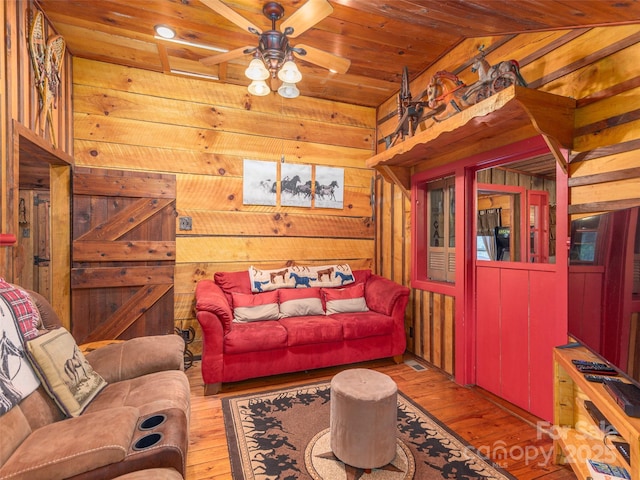 living room with hardwood / wood-style floors, wood walls, wood ceiling, and ceiling fan