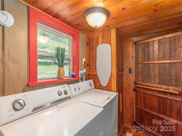laundry area featuring wood ceiling, wood walls, washer and clothes dryer, and laundry area