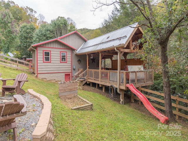 rear view of house featuring fence, a lawn, and a wooden deck