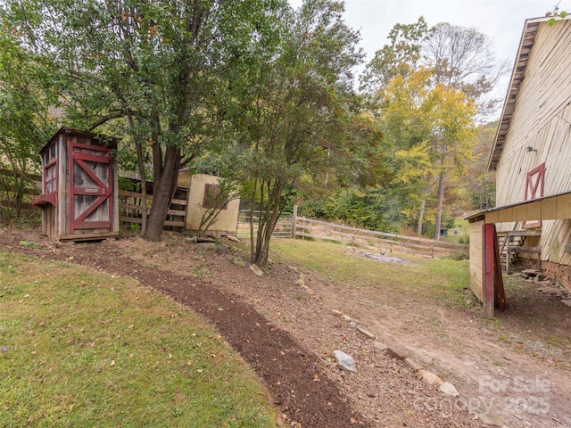 view of yard with an outdoor structure, fence, and a storage unit