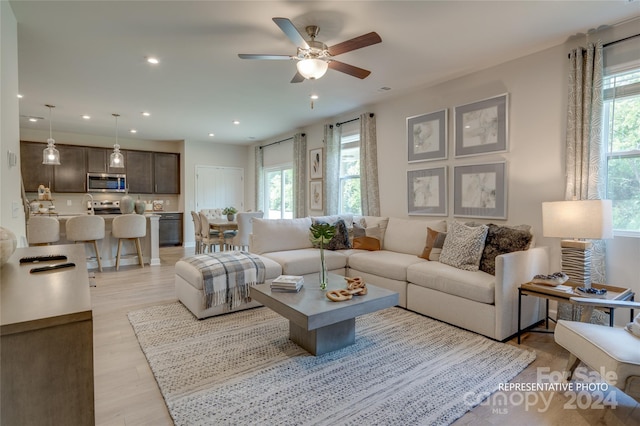 living room with light hardwood / wood-style floors, ceiling fan, and plenty of natural light