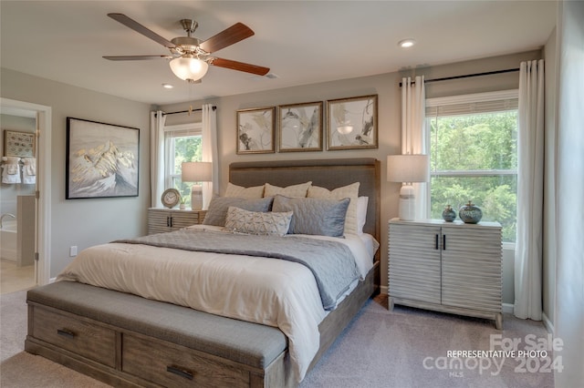 bedroom featuring ceiling fan, light colored carpet, and multiple windows