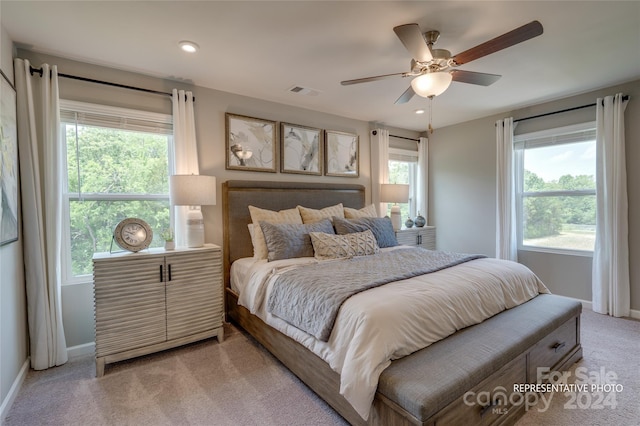 bedroom with multiple windows, light carpet, and ceiling fan