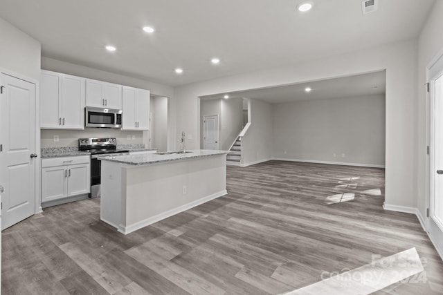 kitchen featuring light hardwood / wood-style flooring, white cabinets, stainless steel appliances, and a center island with sink