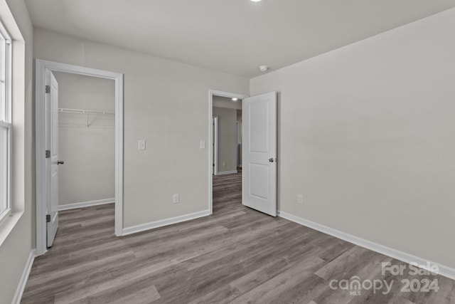 unfurnished bedroom featuring a closet, light hardwood / wood-style flooring, and a walk in closet