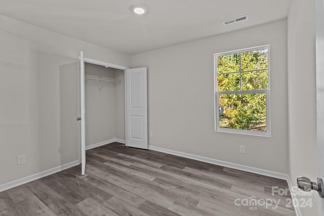 unfurnished bedroom with hardwood / wood-style flooring and a closet