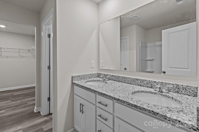 1403 Gentry Pl, Salisbury, NC 28146 - bathroom featuring wood finished floors, a walk in closet, double vanity, and baseboards