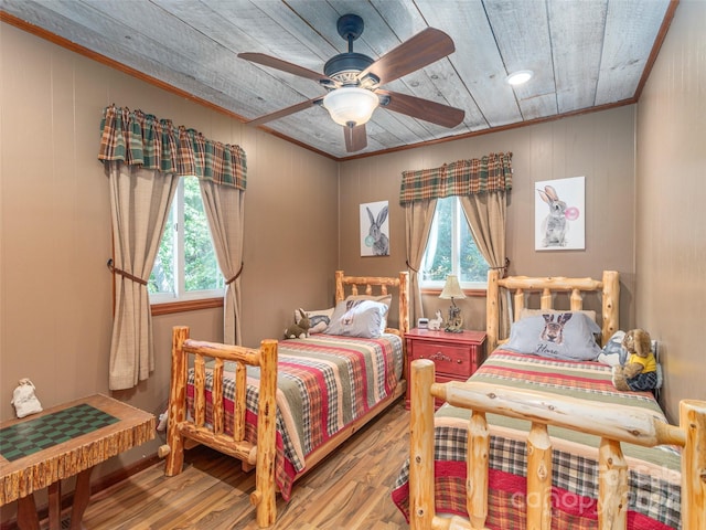 bedroom with ornamental molding, wood walls, hardwood / wood-style floors, wooden ceiling, and ceiling fan