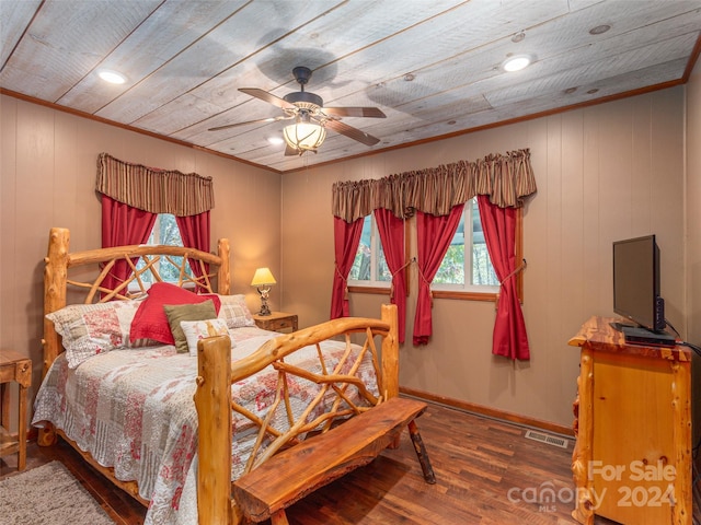 bedroom with wood walls, hardwood / wood-style flooring, ceiling fan, and ornamental molding