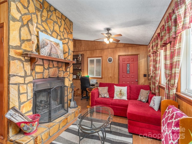 living area featuring wood finished floors, wood walls, a textured ceiling, and ceiling fan