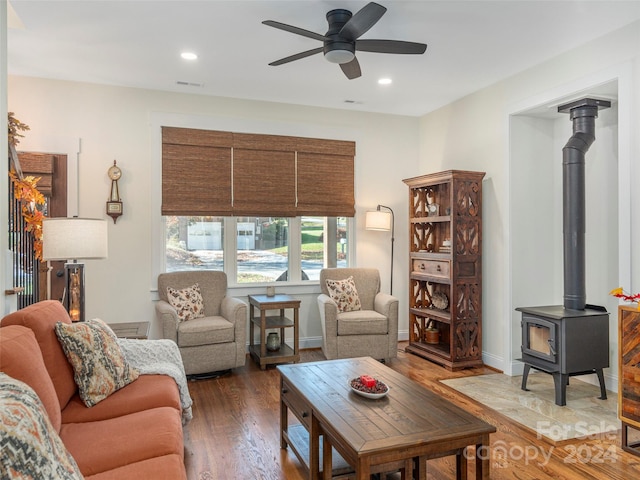 living room featuring ceiling fan, dark hardwood / wood-style flooring, and a wood stove