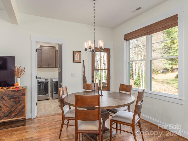 dining room featuring washing machine and dryer, light wood-type flooring, and an inviting chandelier