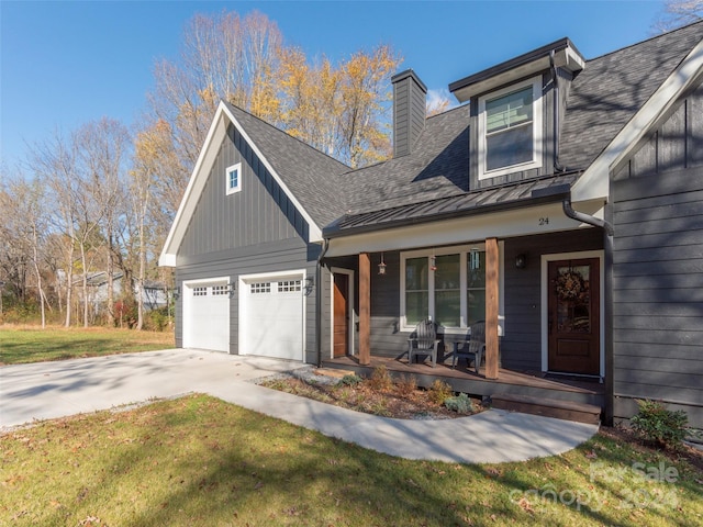 view of front of home with a garage, covered porch, and a front yard