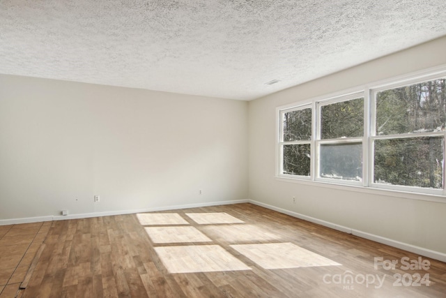 spare room featuring a textured ceiling and hardwood / wood-style flooring