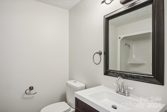 bathroom with vanity, toilet, and a textured ceiling