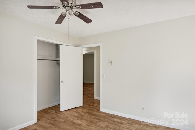 unfurnished bedroom with a textured ceiling, a closet, hardwood / wood-style flooring, and ceiling fan