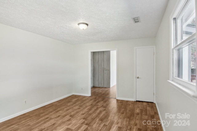 spare room featuring a textured ceiling and hardwood / wood-style flooring