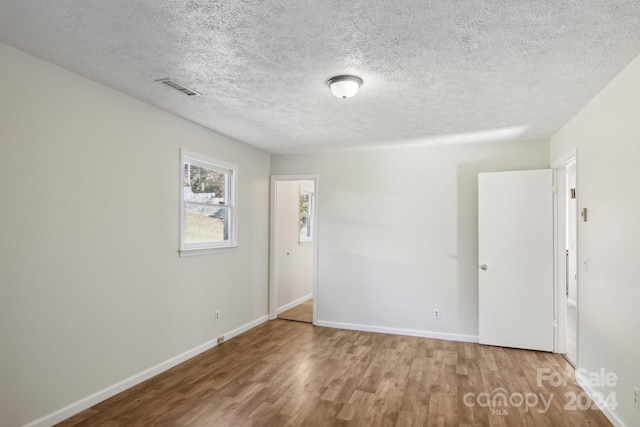 empty room featuring wood-type flooring and a textured ceiling