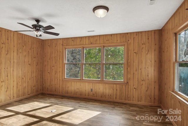 empty room featuring hardwood / wood-style floors, a wealth of natural light, and wooden walls