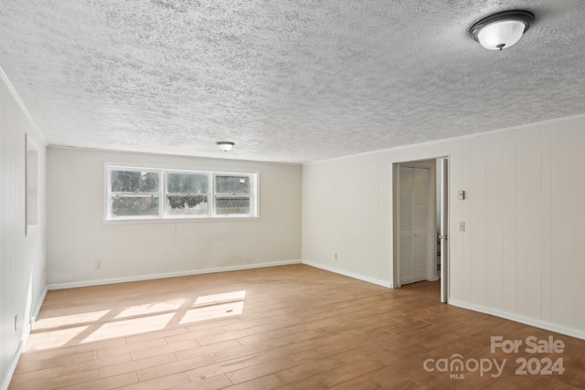 spare room featuring light wood-type flooring and a textured ceiling