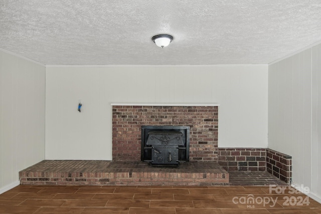 unfurnished living room with a wood stove, wooden walls, dark hardwood / wood-style floors, and a textured ceiling