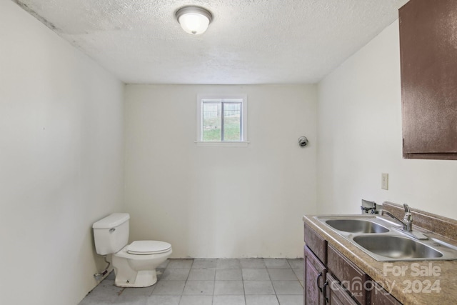 bathroom featuring vanity, tile patterned floors, a textured ceiling, and toilet