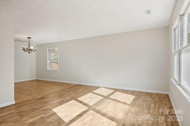 821 Anne Ave W, Hendersonville, NC 28739 - empty room featuring wood finished floors, a chandelier, baseboards, and a textured ceiling