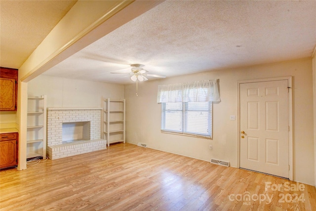 unfurnished living room featuring a fireplace, a textured ceiling, and light hardwood / wood-style flooring