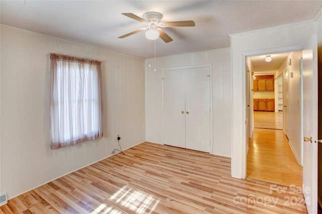 unfurnished bedroom with light hardwood / wood-style floors, ceiling fan, a textured ceiling, and a closet